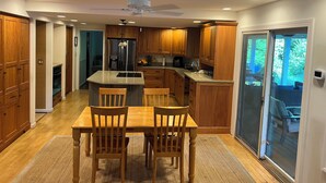 Una cocina moderna con armarios de madera, una isla central y un área de comedor con dos sillas.