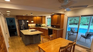 Una cocina moderna con armarios de madera, una isla central y una zona de comedor con sillas.
