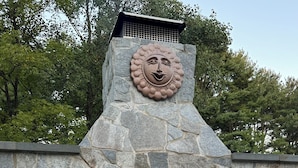 Una chimenea de piedra con un detalle decorativo encima, rodeada de paredes de piedra.