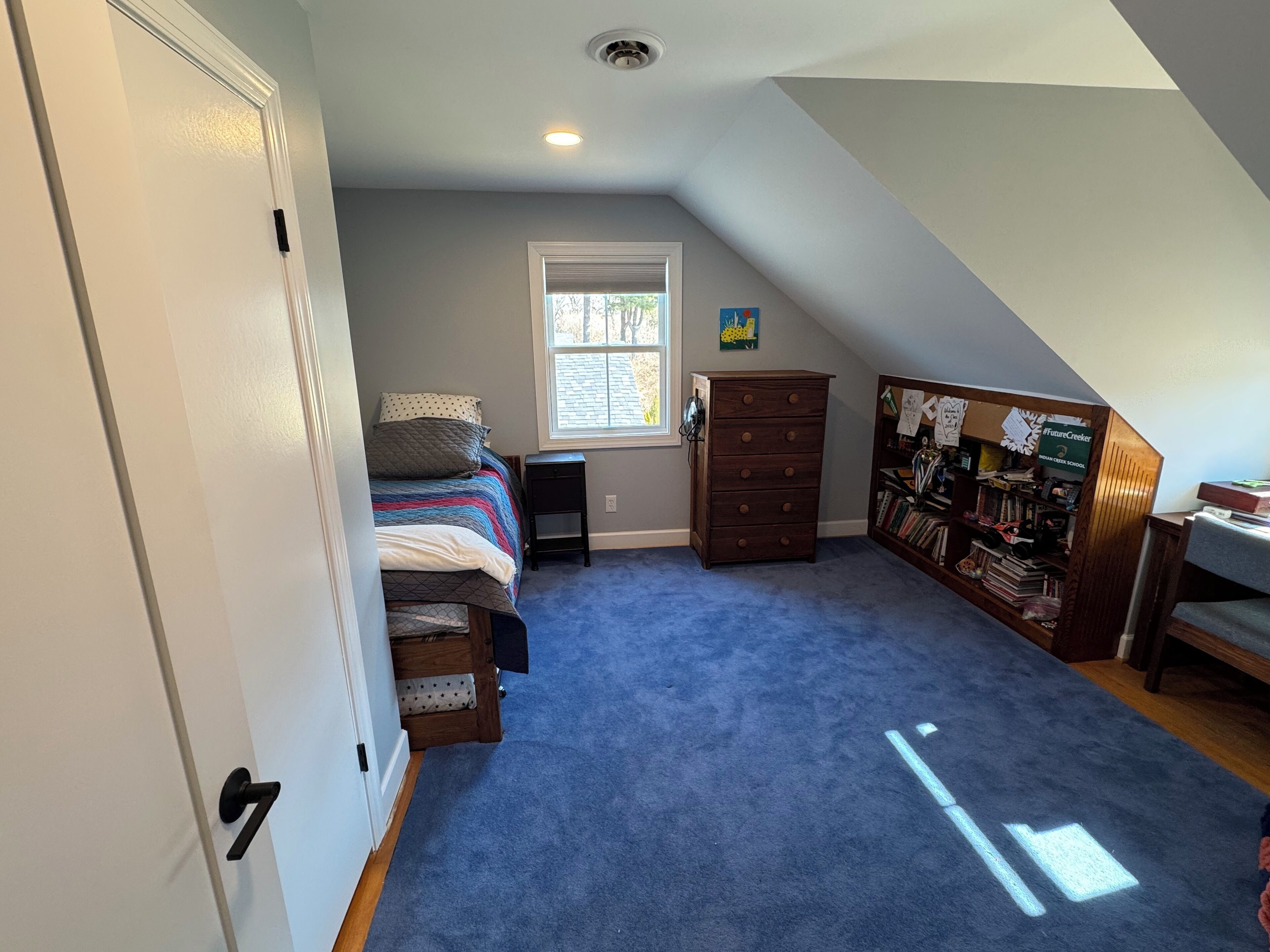 A bedroom with a bed, dresser, and a bookshelf.