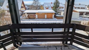 A wooden bench with a view of a residential area covered in snow. - Schwarzwaldmarie Titisee bathtub kitchen balcony underground parking near the lake! (Titisee-Neustadt)