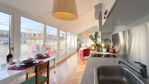 Una cocina moderna con un amplio ventanal, un comedor con mesa para dos personas y vistas a la ciudad.