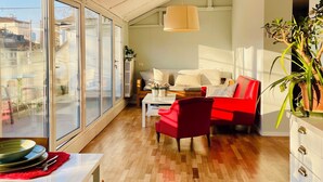 Una sala de estar moderna con un sofá, un sillón rojo y un comedor con mesa y sillas.
