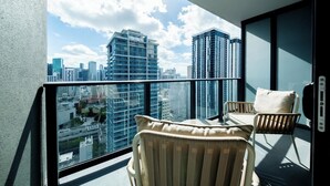 Ein Balkon mit Blick auf die Stadt, zwei Korbstühle und eine Glastür.