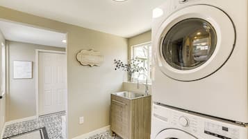 A laundry room with a washing machine, a sink, and a cabinet.