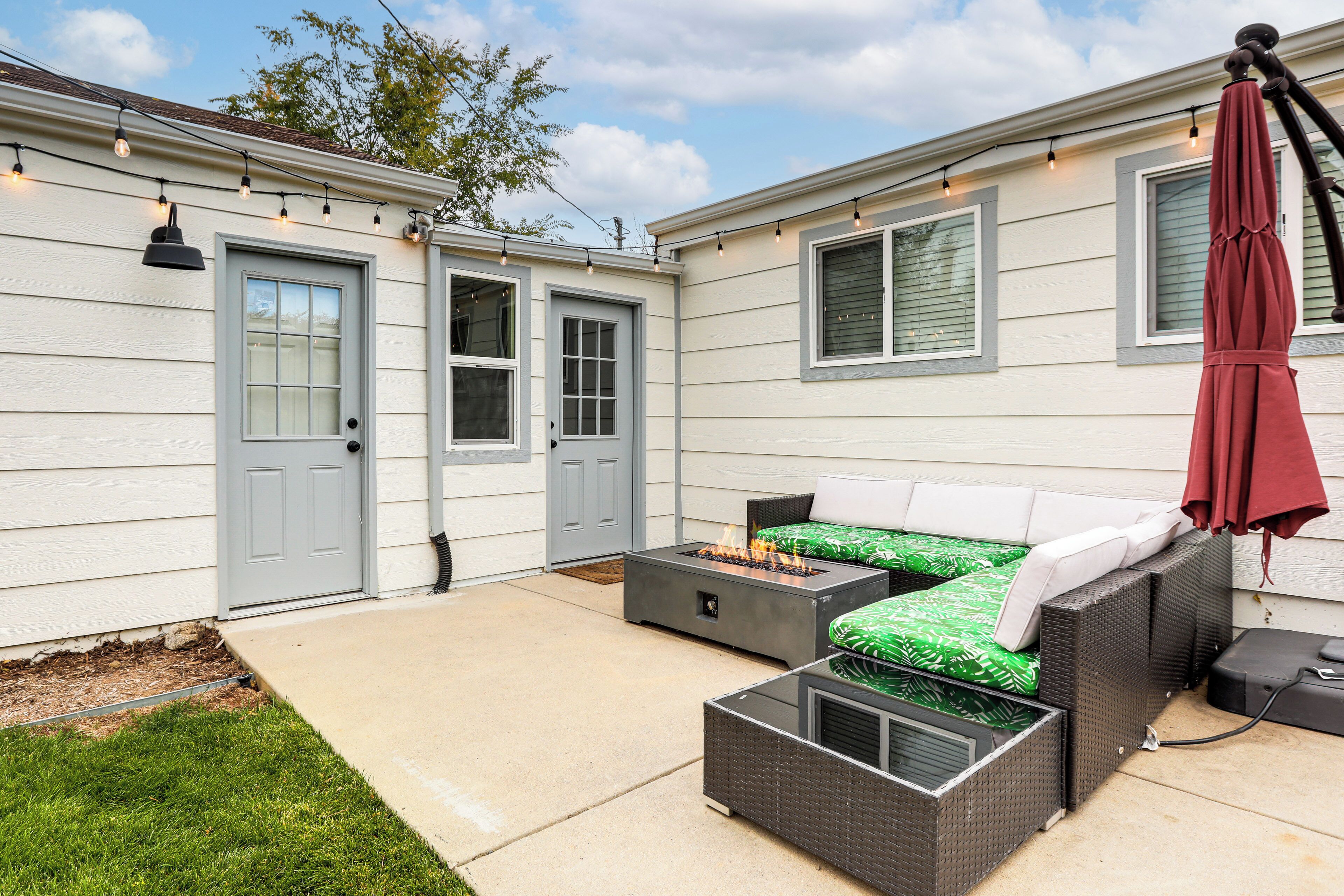 A patio with outdoor furniture, a fire pit, and string lights.
