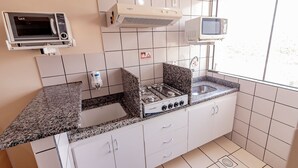 Een kleine keuken met een gasfornuis, magnetron en inbouwoven.