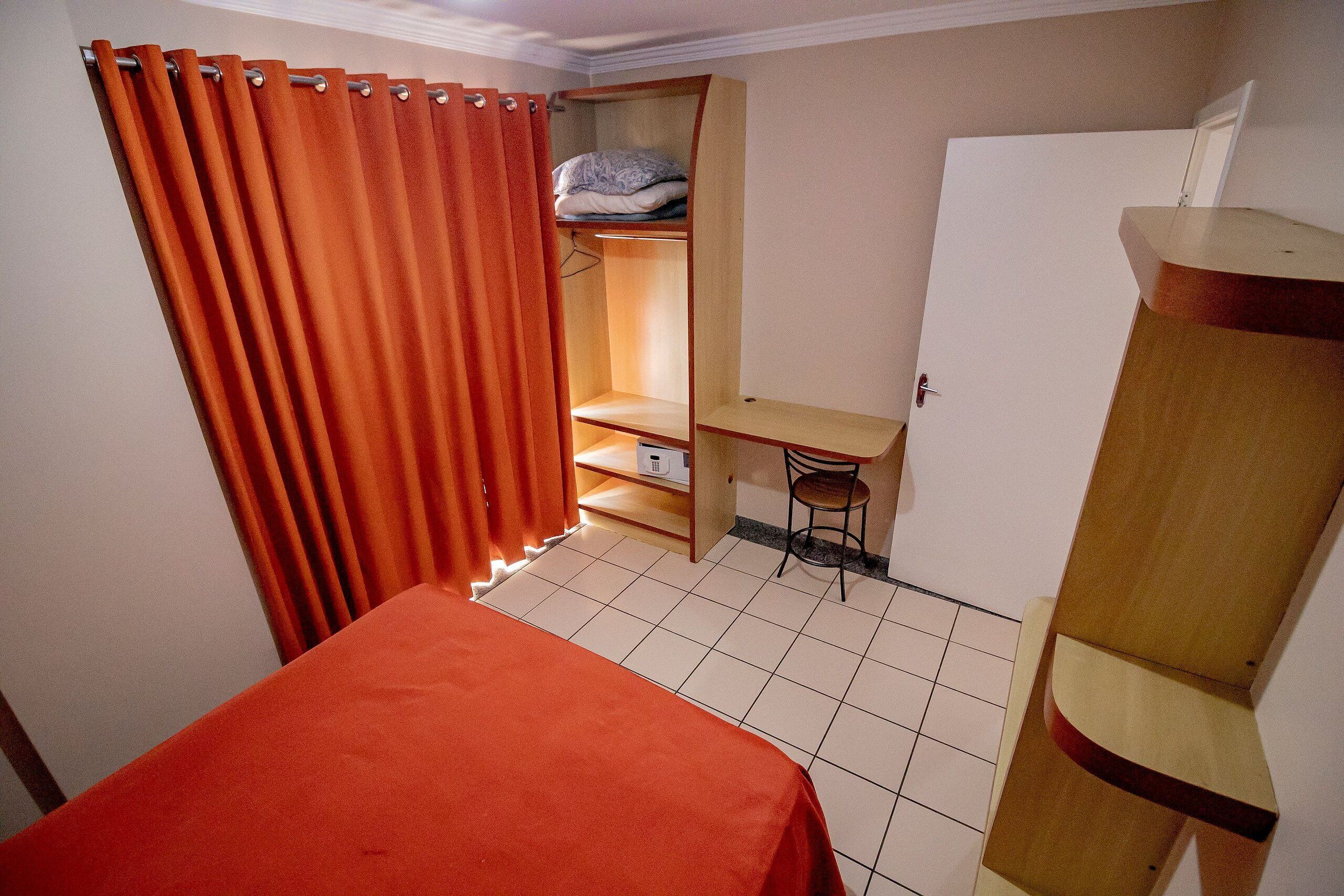 A small, compact room with a bed, a desk, and a wardrobe.