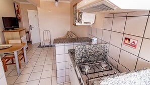 Een kleine keuken met een gasfornuis, een magnetron en een plafondventilator.
