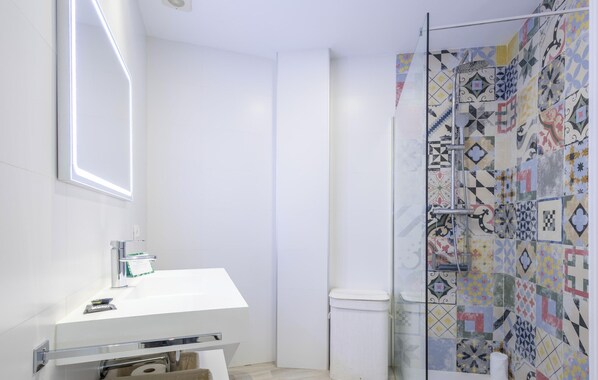 A modern bathroom with a white sink, a glass shower enclosure, and patterned tiles. - Ref. 521865 (Nerja)
