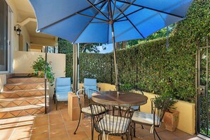 A patio with a round table and chairs, a blue umbrella, and a staircase. - Santa Barbara Luxury Beach Getaways (Santa Barbara)