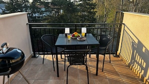 Ein Balkon mit einem Tisch für zwei Personen, ausgestattet mit einer Obstplatte und Gläsern Saft.