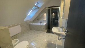 Ein modernes Badezimmer mit Dachfenster, einer Badewanne, einer Duschkabine und einem Waschbecken.