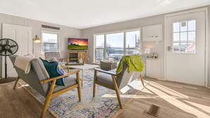 Amplia sala de estar con chimenea, ventanas grandes y vista a la ciudad.