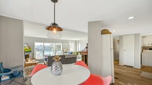 Una sala de estar moderna con una mesa redonda, sillas rojas y una piña decorativa como centro de mesa.