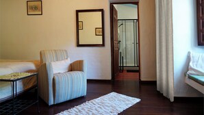 Een kamer met een bed, een gestreept fauteuil, een tafeltje, een spiegel en een deur naar een badkamer.