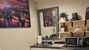 Une cuisine moderne avec des meubles blancs, un four à micro-ondes et un réfrigérateur en acier inoxydable.