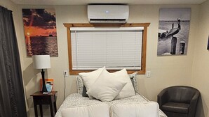 Une chambre à coucher avec un lit, une chaise, un tapis et des œuvres d’art murales.