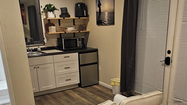 Une chambre avec un lit, une petite kitchenette et une porte donnant sur une autre pièce.