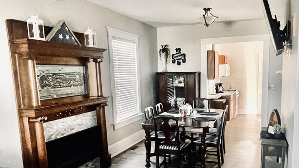 A living room with a fireplace, dining table, and chairs. There is a kitchen in the background. - Cedar Point - Sandusky Themed House (Sandusky)
