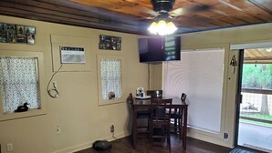 Un coin repas comprenant une table et des chaises, un ventilateur de plafond et un téléviseur fixé au mur.