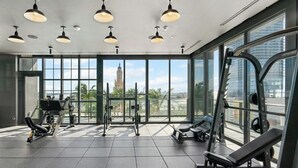 A gym with large windows, exercise equipment, and pendant lighting.