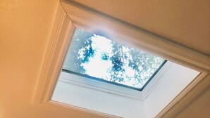 Ein Zimmer mit Dachfenster, einem gerahmten abstrakten Gemälde und einer weißen Tür.