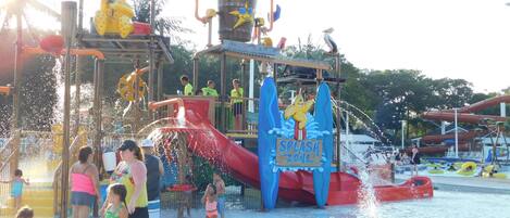 Parque acuático con zona de juegos, toboganes y piscina.