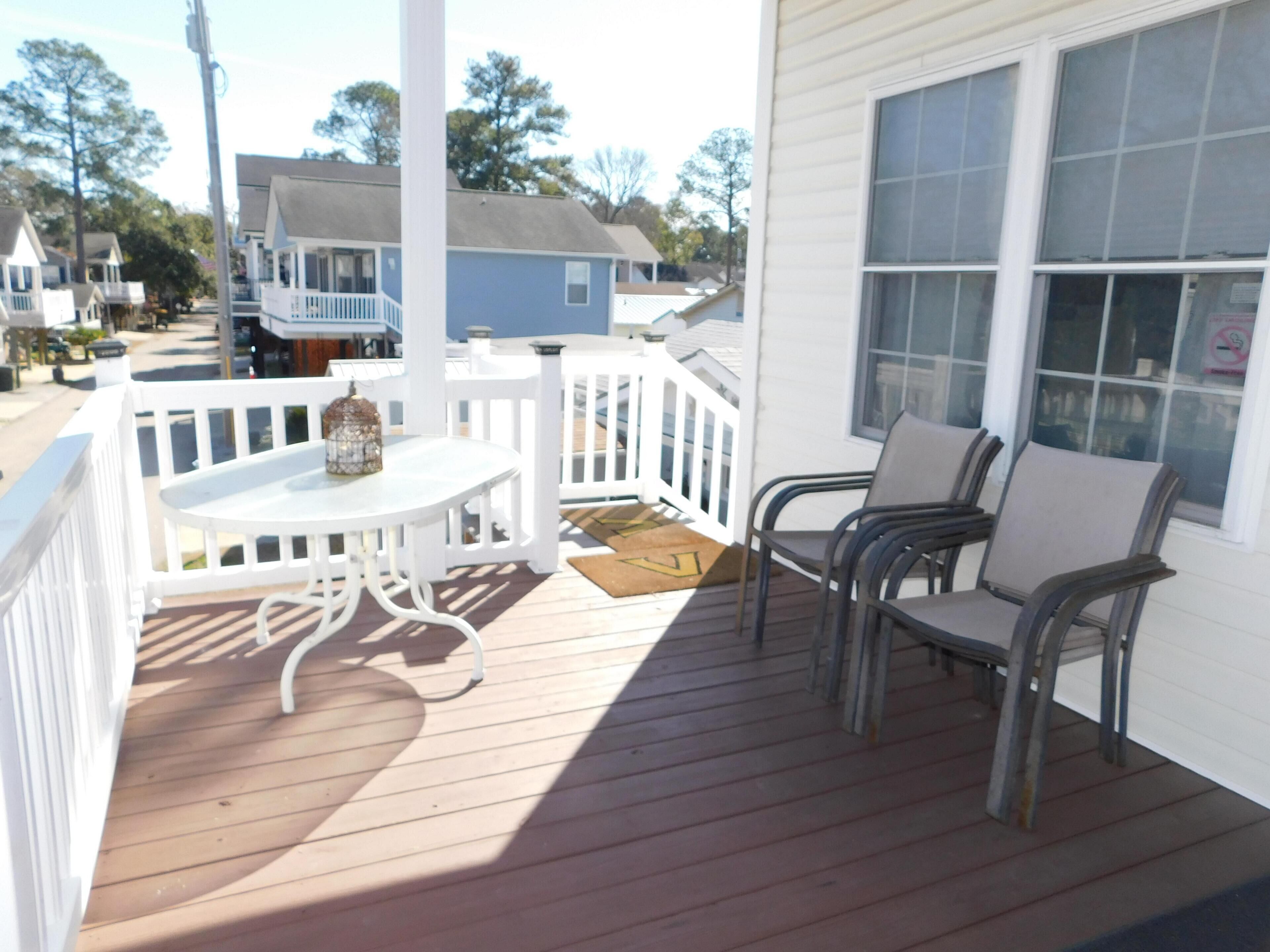 A wooden deck with a white railing, a table, and two chairs.
