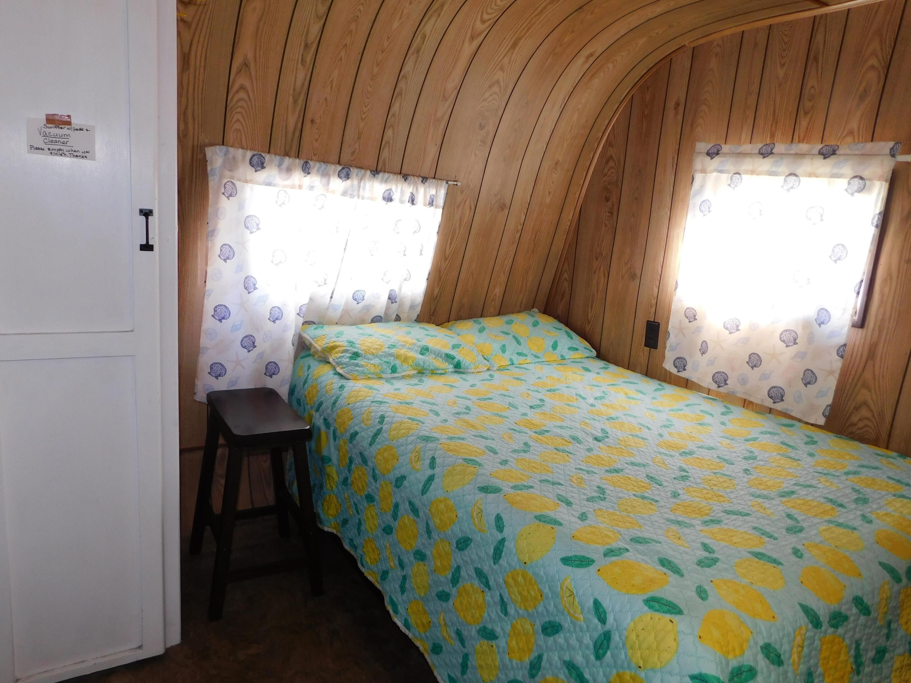 Een knus, klein kamertje met een bed, een bureau en een stoel.
