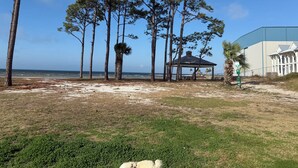 A beach area with a gazebo, tall pine trees, and a large building in the background. - Awesome  condo in The Marina. At Port St. Joe. 
 Bay views, exciting night life (Port St. Joe)