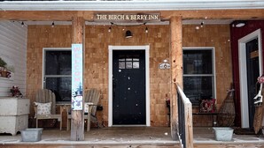 Ein Holzgebäude mit einer schwarzen Tür und einem Schild mit der Aufschrift 'The Birch & Berry Inn'.