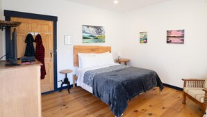 Ein Schlafzimmer mit einem hölzernen Bett, einem Schreibtisch, einem Stuhl und Bildern an den Wänden.