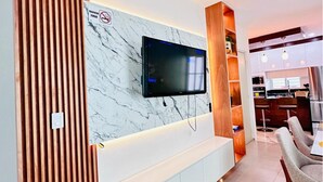 Een moderne woonkamer met een televisie die aan een marmeren muur is bevestigd, een houten paneel en een witte entertainmentkast.
