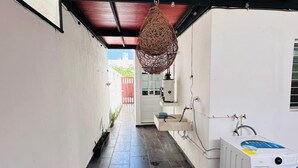 Een smalle gang met een wasmachine en een hanglamp.