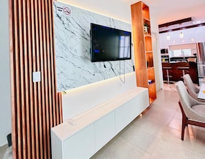 A modern living room with a TV mounted on a marble wall, a wooden panel, and a white entertainment unit. - Casa Gran Santa Fe 25 minutes from Playa Lobster beach, Cancun hotel zone. (Cancún)