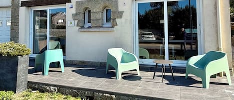 Una casa a due piani con facciata in pietra, numero 8, con un patio e arredi da esterno, oltre a un'ampia finestra.