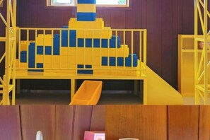 A play area with a yellow and blue play structure, a slide, and a small enclosed space. - Nangong Hot Spring Health Hotel (Beijing)