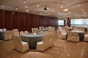 A banquet hall with round tables and chairs, a polished floor, and a large screen at the front. - Nangong Hot Spring Health Hotel (Beijing)