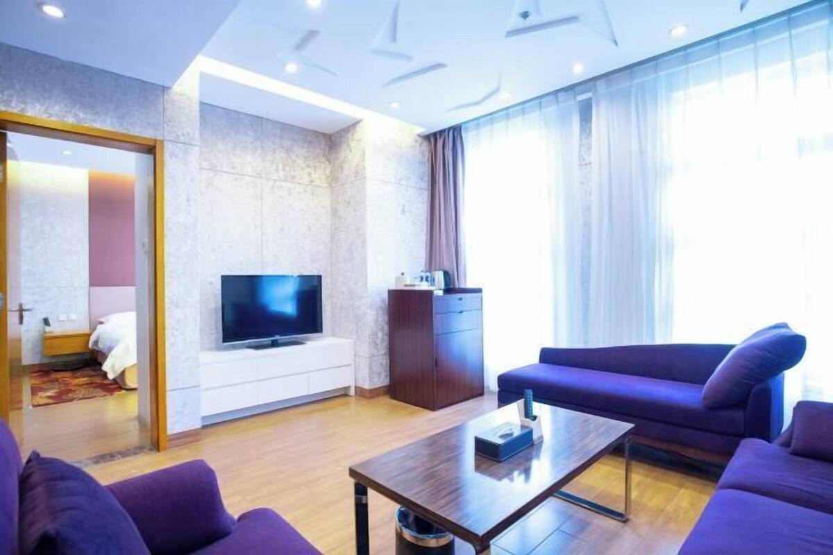 Ein modernes Wohnzimmer mit Flachbildfernseher, einer Couch, einem Couchtisch und einem Schrank.