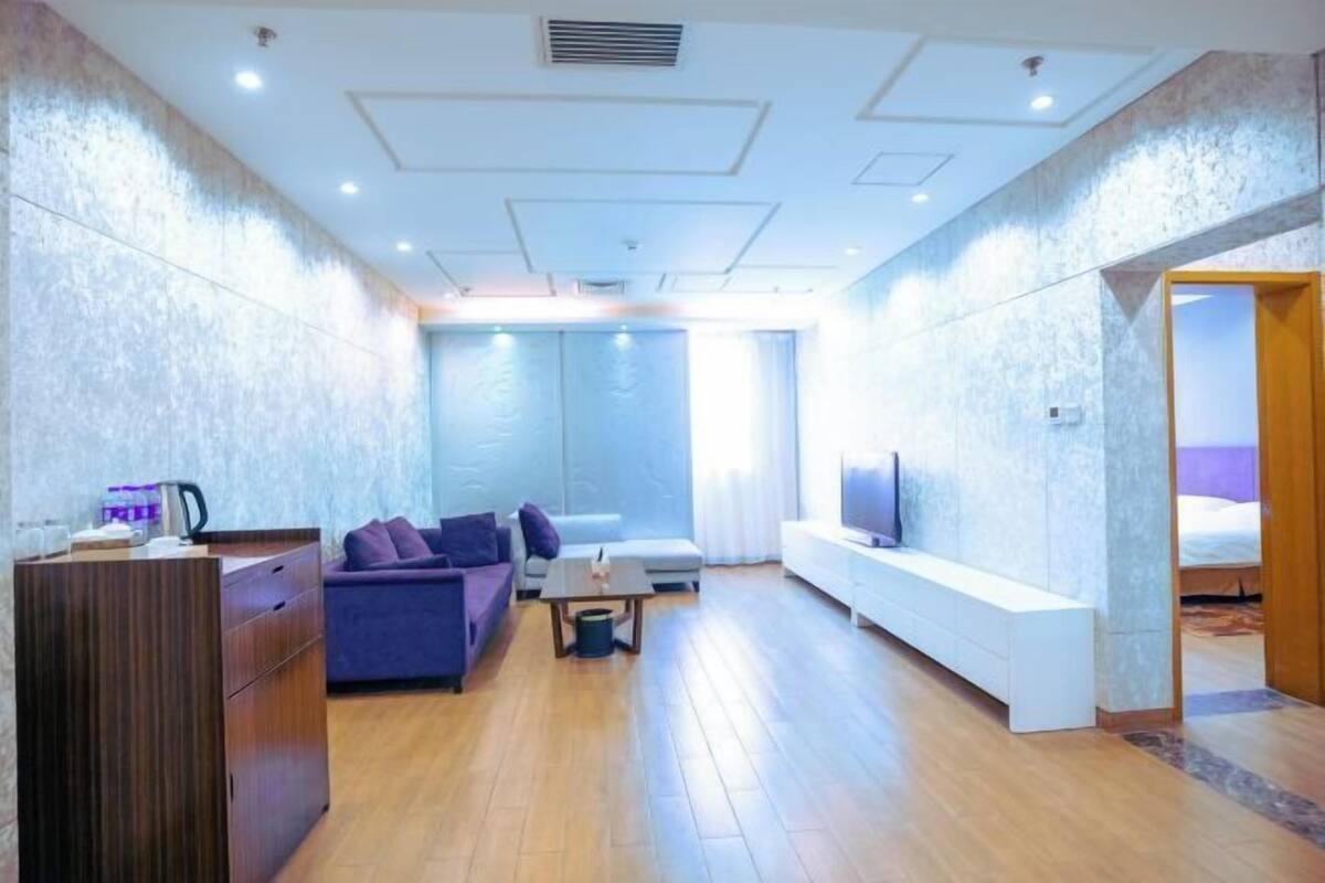 Ein modernes Hotelzimmer mit Holzboden, einer Couch, einem Fernseher und einem Schreibtisch.
