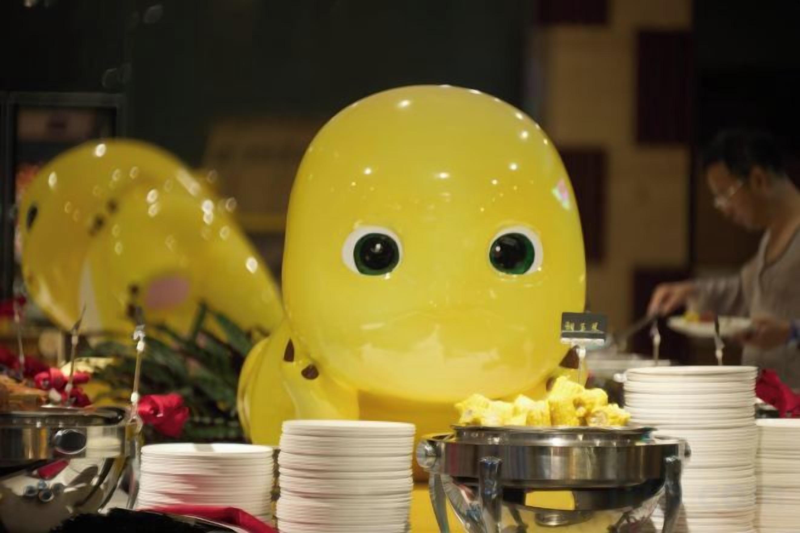 A buffet setup with food containers and a large yellow balloon decoration.