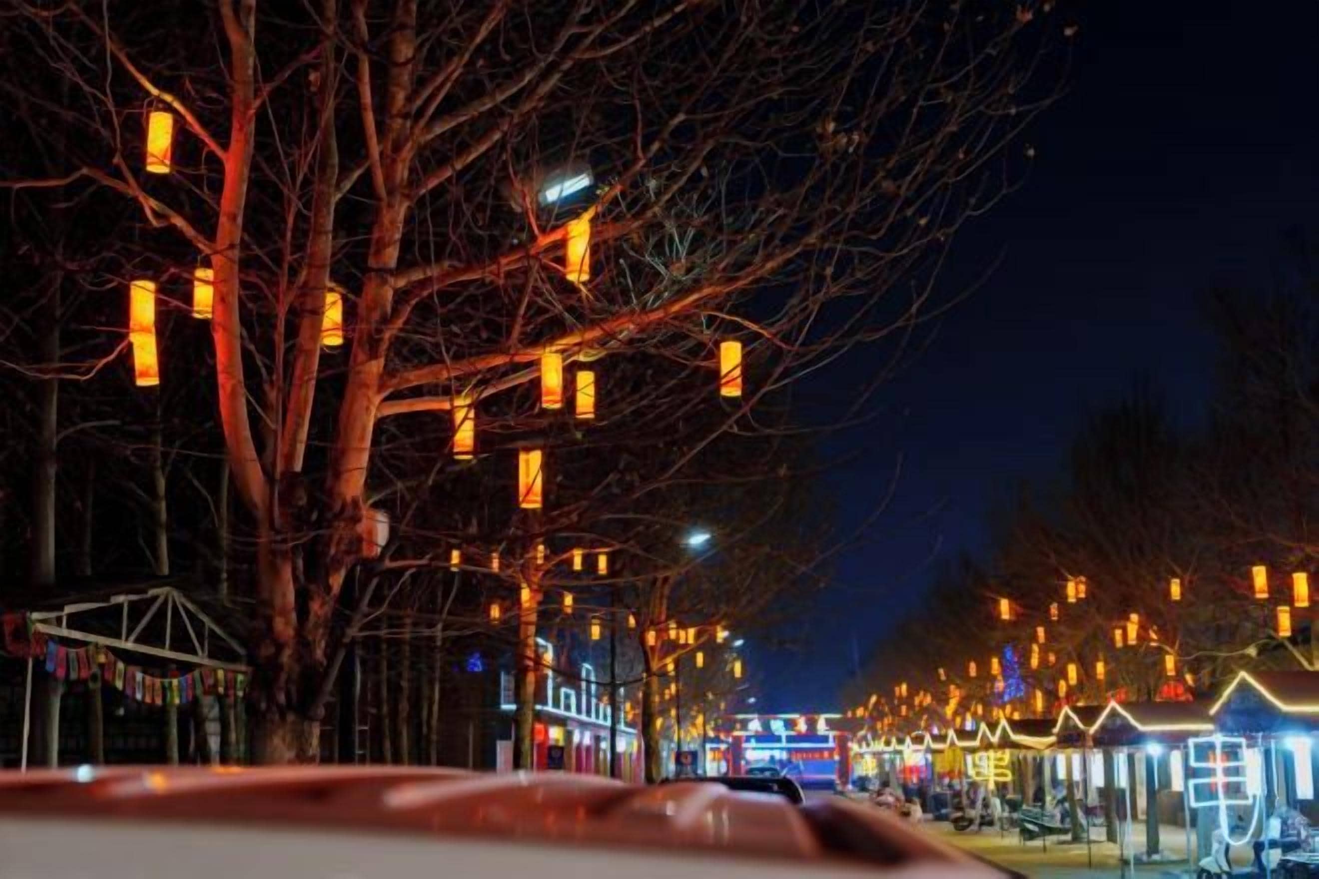 A nighttime street scene with illuminated street lamps and buildings.