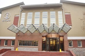 A building with a modern architectural design, featuring a prominent entrance with a glass canopy and a set of stairs leading up to it. - Nangong Hot Spring Health Hotel (Beijing)
