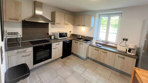Een moderne keuken met lichte houten kastjes, een ingebouwde oven, een magnetron en een spoelbak.