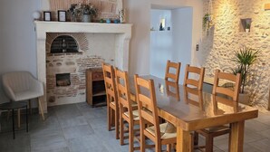 Een eethoek met een schouw van baksteen, houten stoelen en een betegelde vloer.
