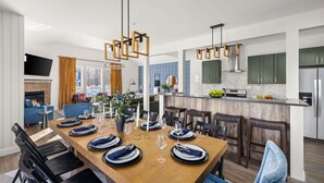 A modern kitchen with a central island, built-in appliances, and a dining area with a wooden table set for six.