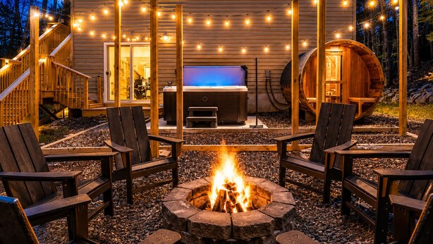 A wooden deck with a fire pit, outdoor seating, and string lights.