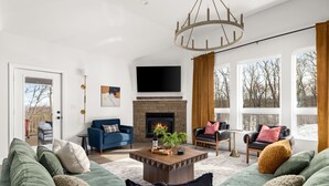 A modern living room with a fireplace, large windows, and a cozy seating area.