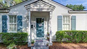 A white house with the number 605, a blue door, and a welcome mat.